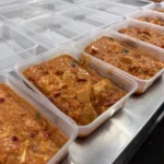 Freshly prepared meals being packed into takeaway containers at Soul Hub's community kitchen in Newcastle, Australia.