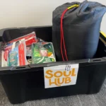 Soul Hub donation container filled with essential supplies, supporting Pacific International Insurance's Soft Landings Foundation community initiatives.